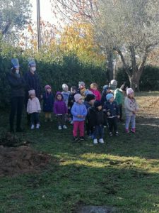 Bambini che assistono alla piantumazione di alberi e alla lettura di una storia